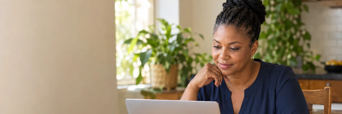 Self-employed woman reviewing her figures on a laptop at a kitchen table