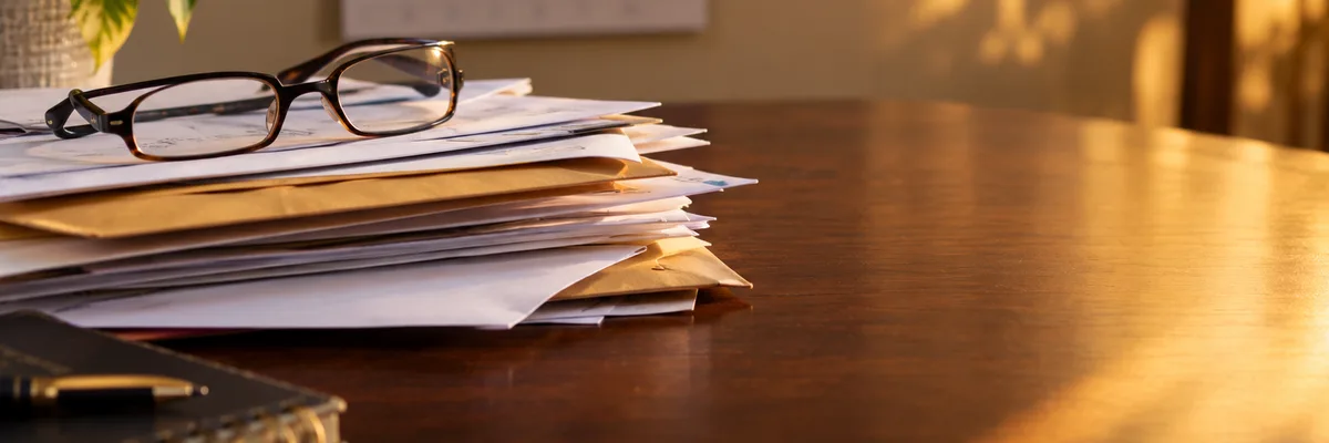 A pile of unopened envelopes and papers on a desk